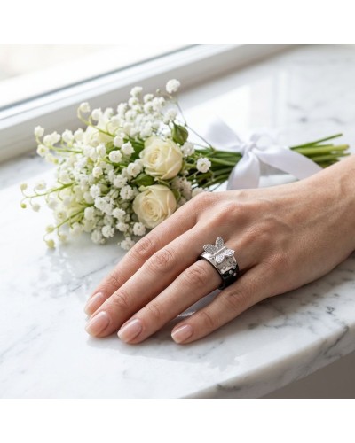 Alliance KUPU-KUPU : doigt portant une bague élégante avec motif fleur et pierres, sur fond bouquet de fleurs blanches sur marbr