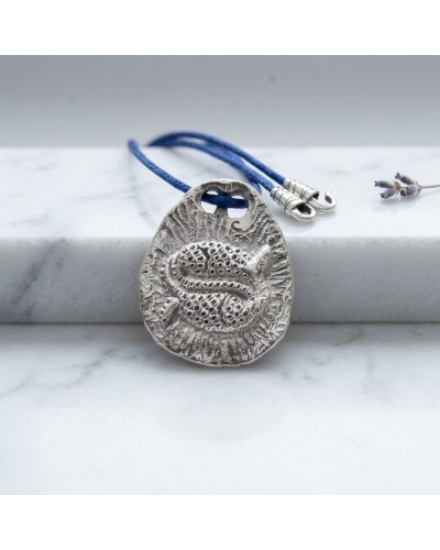 Pendentif zodiaque Poisson gravé sur pierre argentée, corde bleue avec fermoir offert, posé sur surface blanche.