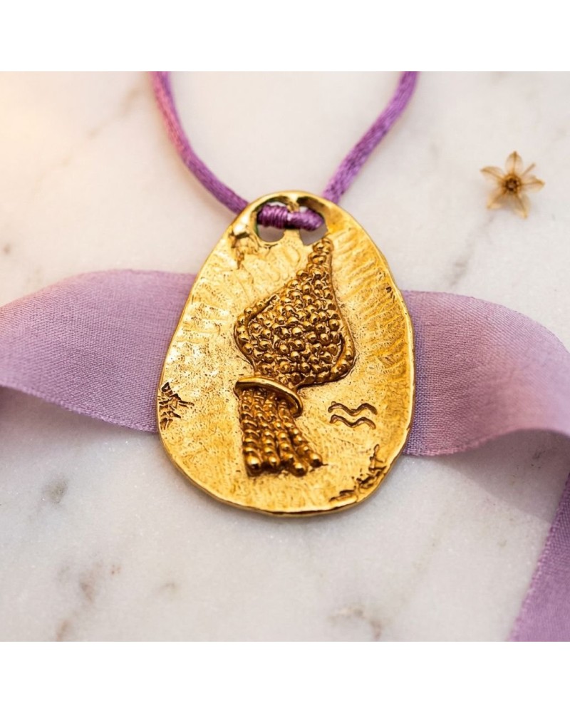 Pendentif zodiaque Verseau en or avec cordon violet et fermoir offert, motif plume/texturé sur plaque ovalisée.