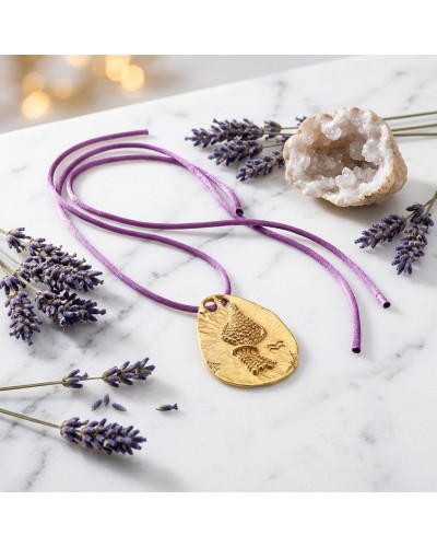 Pendentif zodiaque Verseau en or gravé, cordon violet avec fermoir offert, posé sur marbre avec cristaux et lis lavande.