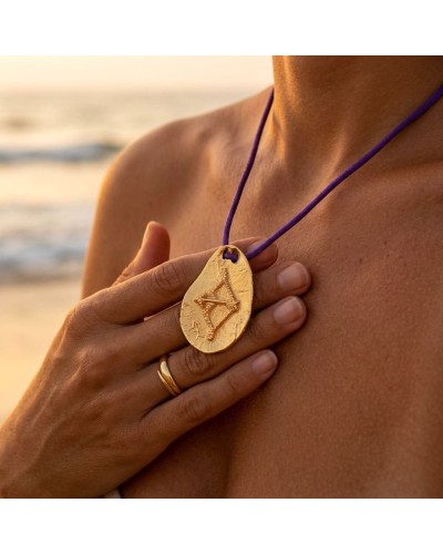Pendentif zodiac SAGITTAIRE en or, gravé, porté au collier violet avec fermoir offert, posé sur la poitrine près de la clavicule