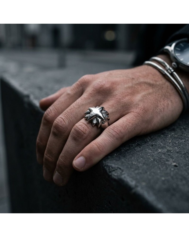 Bague ETOILE en métal argenté avec étoile centrale et motifs étoilés, portée sur le doigt d'une personne près d'un mur gris.