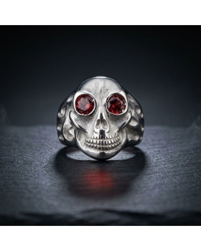 Bague en forme de crâne argenté avec yeux rouges facettés, thème sombre et skull, "Bague CORSAIRE" mentionnée comme produit.