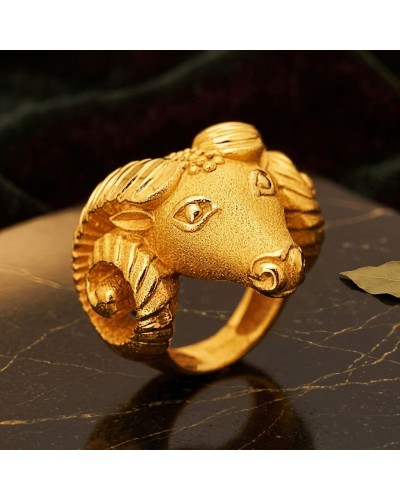 Bague dorée en forme de bélier, finition texturée, design sculpté avec cornes et visage détaillé. Mannequin sur un fond sombre.