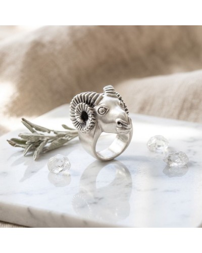 Bague argentée MOUFLON en forme de tête de bélier, avec cornes torsadées et détail sculpté, posée sur marbre avec pierres décora