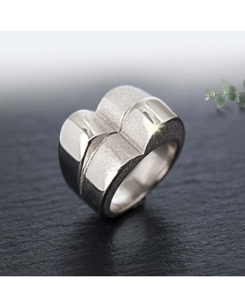 Bague BOSSA NOVA en métal argenté avec motif géométrique rehaussé par une texture mate sur fond noir.