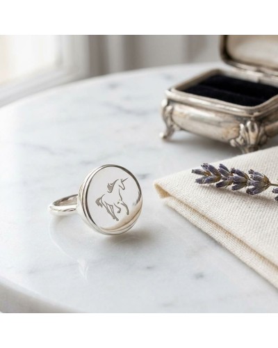 Bague ronde en argent rhodié gravée du logo Murial, montre un cheval stylisé sur un disque lisse.