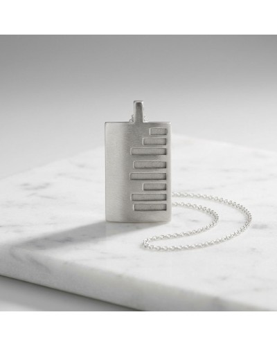 Pendentif rectangulaire argenté avec motif de barres horizontales, chaîne fine, posé sur marbre. Pendentif KEKAYAAN. Chaîne offe