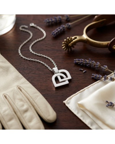 Pendentif en forme de cœur géométrique argent rhodié sur chaîne, posé sur bois avec des gants clairs et des brins de lavandes.