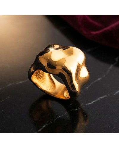 Bague BOSSE en métal doré, forme organique fluide, reflet brillant sur une surface sombre.