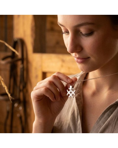 Pendentif TREFLE DE FERS en argent rhodié porté sur une chaîne, posé près du collier par une femme dans un décor en bois.
