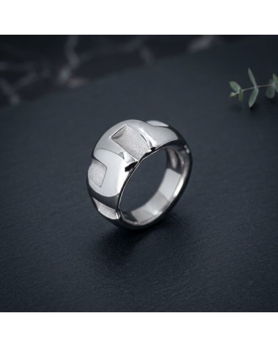 Bague GREC en acier argenté, design moderne à facettes géométriques, portée sur fond sombre.