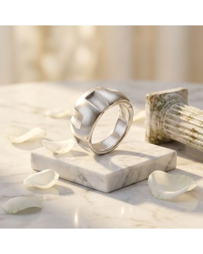 Bague GREC en argent moderne, posé sur un socle de marbre blanc, entourée de pétales blancs et d’un morceau de bois décoratif.