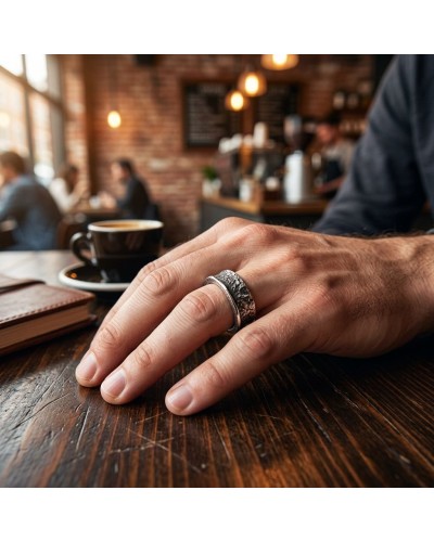 Aucune image visible? Bague ANNEAU SERRE portée sur le doigt posé sur une table en café, fond blurred.