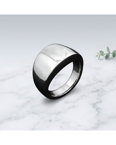 Bague BALI: anneau noir et argenté dépoli, design épuré sur surface marbrée avec petite plante à côté.