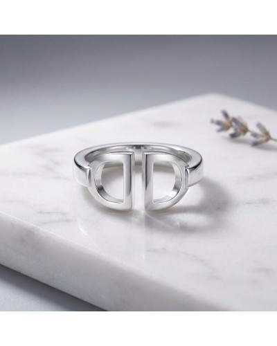 Bague femme en argent rhodié, design moderne avec deux loops formant un motif symétrique sur une pierre blanche.