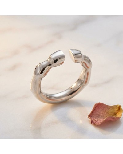 Bague TROT femme en argent rhodié, design ouverte avec extrémités en forme de bouchon, sur fond marbre clair avec pétale séché.