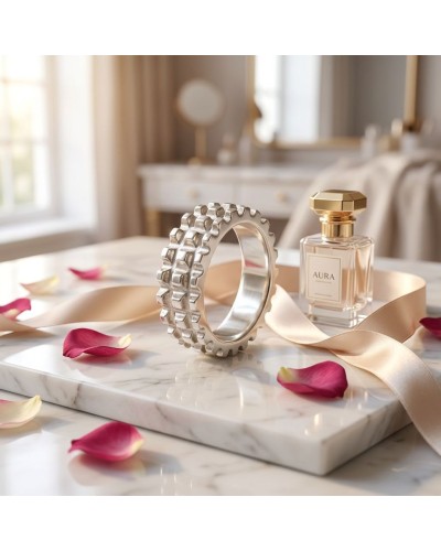 Alliance TEMPS MODERNE femme en or: bracelet argenté muni de motifs géométriques posé sur un marbre, avec parfum AURA et ruban r
