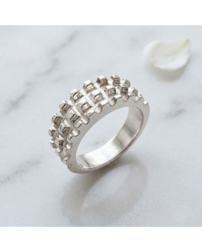 Alliance TEMPS MODERNE femme en or : bague argentée à motifs géométriques carrés, cadrant au centre du cadre sur fond marbré.