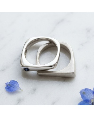 Alliance PYRAMIDE en or sertie d'un saphir bleu, anneau moderne en or jaune avec pierre bleue sur marbre.