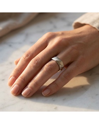 Alliance DRAPE en or sur doigt, bague aux arêtes facettes argentées portée sur une main au repos.