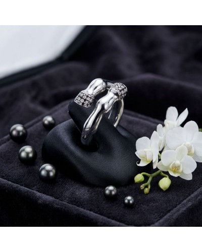 Bague femme en argent rhodié sertie de 42 oxydes noirs, présentée sur coussinet noir avec perles et fleurs blanches.
