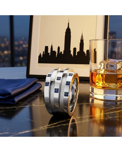 Bague NEW YORK en argent rhodié, sertie de 8 saphirs bleus synthétiques, posée sur une table près d’un verre et d’un cadre noctu