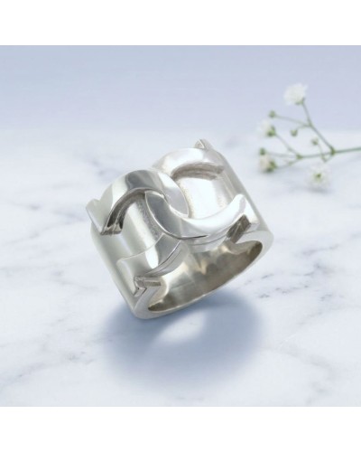 Bague MARECHAL en argent rhodié, anneau large avec motifs géométriques luisants sur fond marbré blanc.