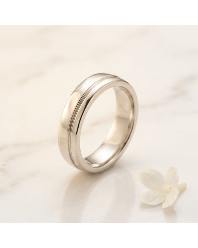 Alliance TRAIT D'UNION pour femme en or: chevalière argentée élégante sur fond clair avec fleur blanche.