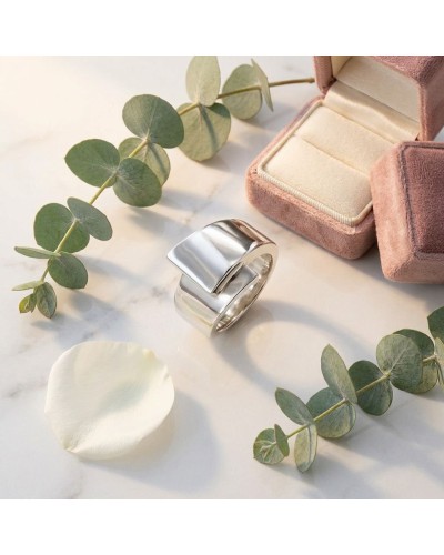 Alliance TOI SUR MOI pour femme en or: bague argentée moderne posée près d’un écrin rose, pétales et eucalyptus.