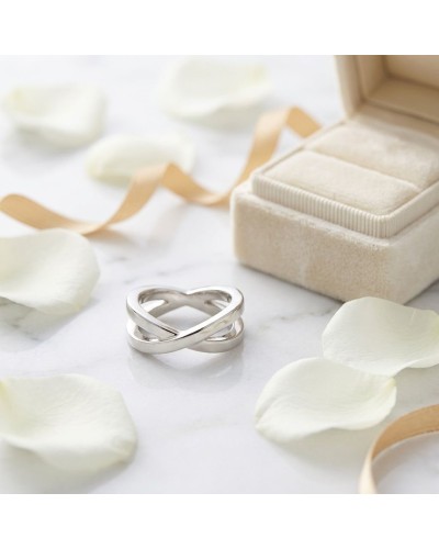 Alliance INSEPARABLE simple pour femme en or: bague argentée en forme d’infini près d’un coffret et pétales blancs.