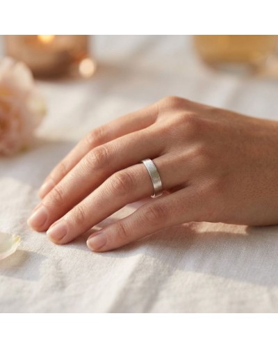 Alliance effet gravé pour femme en or: bague argentée sur doigt féminin, style minimaliste et élégant.