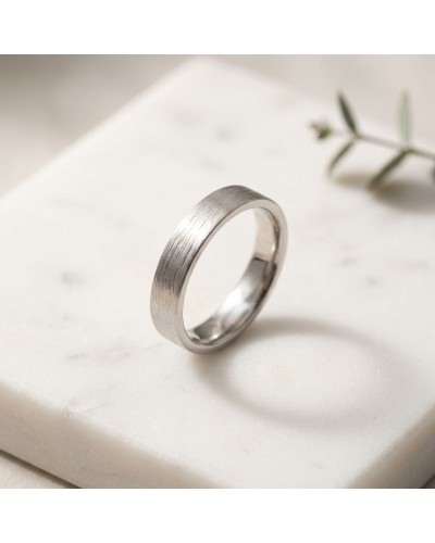 Alliance homme en or argentée au fini brushed sur pierre blanche, montrant une bague épurée et moderne.