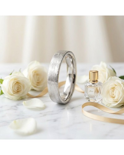 Alliance effet brossé pour femme en or, bracelet argenté posé près de roses et parfum élégant sur marbre blanc.