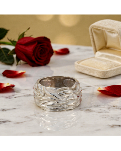 Alliance FLAMME pour femme en or: bague argentée texturée avec motifs ondulés, posée sur marbre, roses rouges et boîte à bijoux