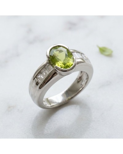 Alliance PRINTEMPS en or avec péridot central et diamants baguette sur le duo de côtés, écrin brillant.