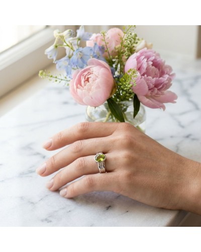 AlliancePRINTEMPS en or sertie d'un péridot et de 6 diamants portée sur une main près d'un bouquet pastel.