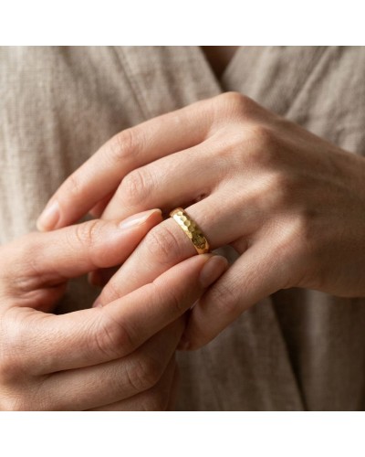Alliance femme bombée martelée en or, bague artisanale sur mesure, dorée, portée sur l’annulaire.