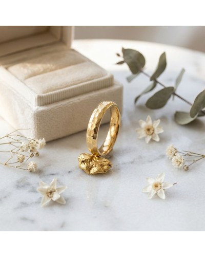 Alliance femme bombée martelée en or— bijou artisanal sur mesure, avec bague dorée martelée posée près d’une boîtes à bijoux et
