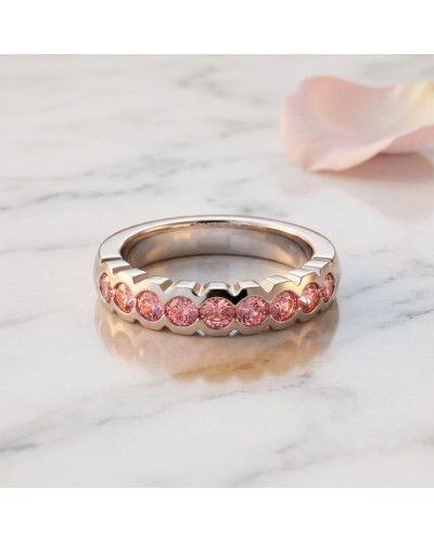 Alliance sertie dans la masse avec 9 saphirs roses synthétiques sur bague en or, vue de côté sur marbre.