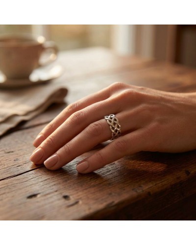 Alliance TRESSE en or: bague délicate en forme de nœud tressé portée sur le dos de la main, sur table en bois.