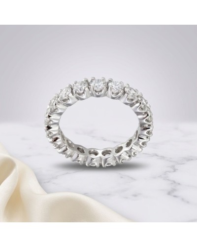 Alliance en or blanc avec 19 diamants sertis autour, anneau perlé et lustre brillant sur marbre.