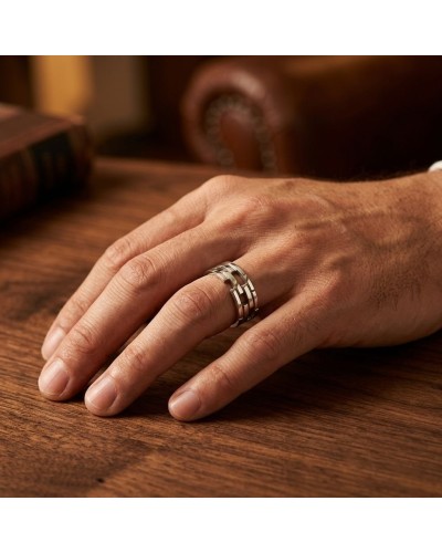 Alliance homme en or argenté sur le doigt, porté sur une main posée sur une table en bois, style élégant.