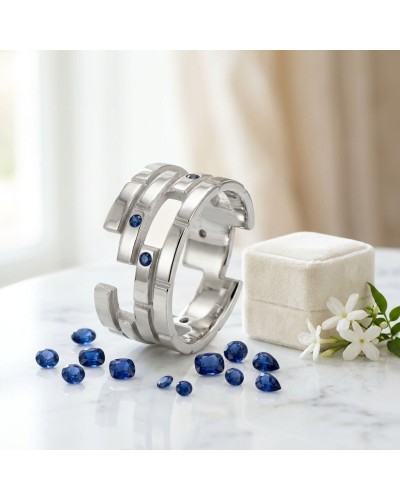 Alliance femme en or sertie de 7 saphirs synthétiques argenté, bracelet moderne posé sur pierre blanche with blue gems autour.