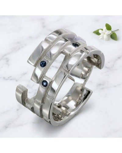 Alliance femme en or sertie de 7 saphirs synthétiques, bague large argentée avec motifs ouverts et pierres bleues sur fond blanc