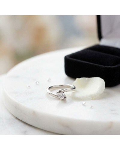 Alliance HALMAHERA en or sertie d'un diamant sur un socle blanc avec pétale et petit écrin noir, ambiance élégante.