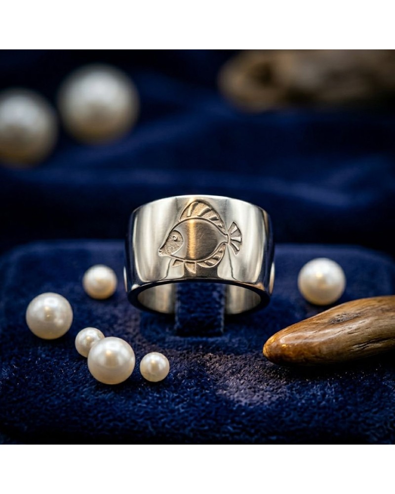 Alliance gravure poisson pour homme en or: bague argentée avec motif poisson, posée sur velours bleu avec perles.