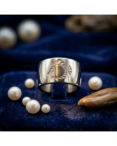 Alliance gravure poisson pour homme en or: bague argentée avec motif poisson, posée sur velours bleu avec perles.