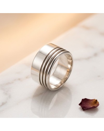 Alliance Large Striée femme en or : bague argentée à larges bandes gravées, posée sur marbre avec pétale sèche.