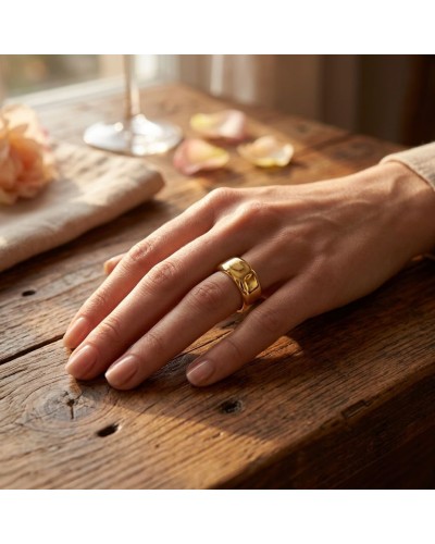 Alliance en or lisse portée sur le doigt d’une main féminine, décor simple sur une table en bois.